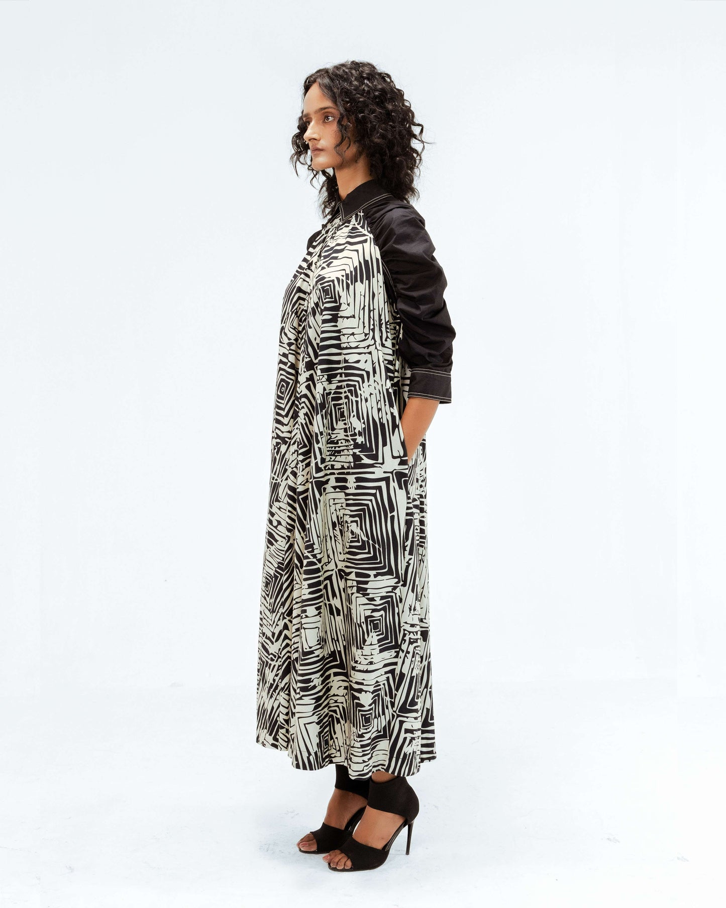 The Leh Studios Florix Print Fable Dress, part of the Rhythm of time collection, features a unique black and white geometric pattern. This luxury upcycled fashion piece highlights sustainable Indian fashion and artisanal craftsmanship, reflecting Leh clothing's commitment to ethical and handcrafted apparel.