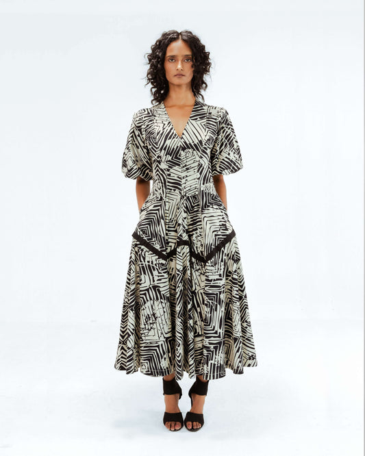 Full-length image of the Leh Studios Florix Print Thalia Dress, an exquisite example of luxury upcycled fashion from the Rhythm of time collection. This black and white abstract geometric print midi dress, featuring a deep V-neck and structured waist detailing, showcases artisanal craftsmanship and ethical fashion principles in its eco-friendly design.