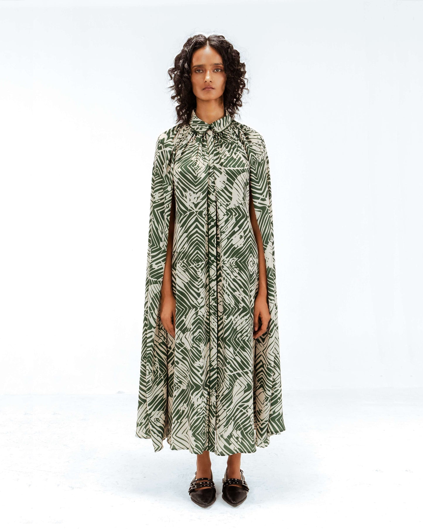 Woman wearing a green and white patterned dress on a white background from Leh Studios.