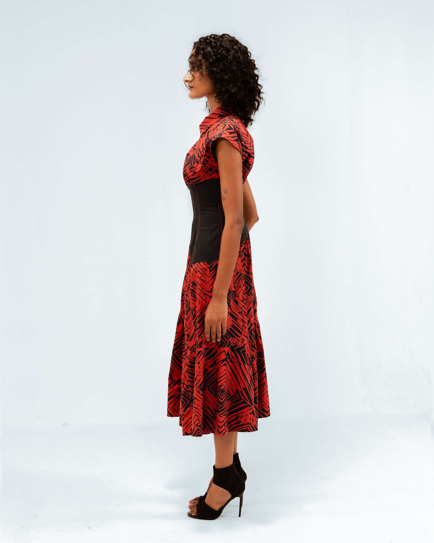 Leh Studios Florix Print Basque Tiered Dress from the Rhythm of time collection, a stunning example of sustainable fashion. This handcrafted organic cotton dress features a vibrant red and black abstract print, a contrasting black basque waist, and a flowing tiered skirt, representing ethical designer wear for women's apparel.