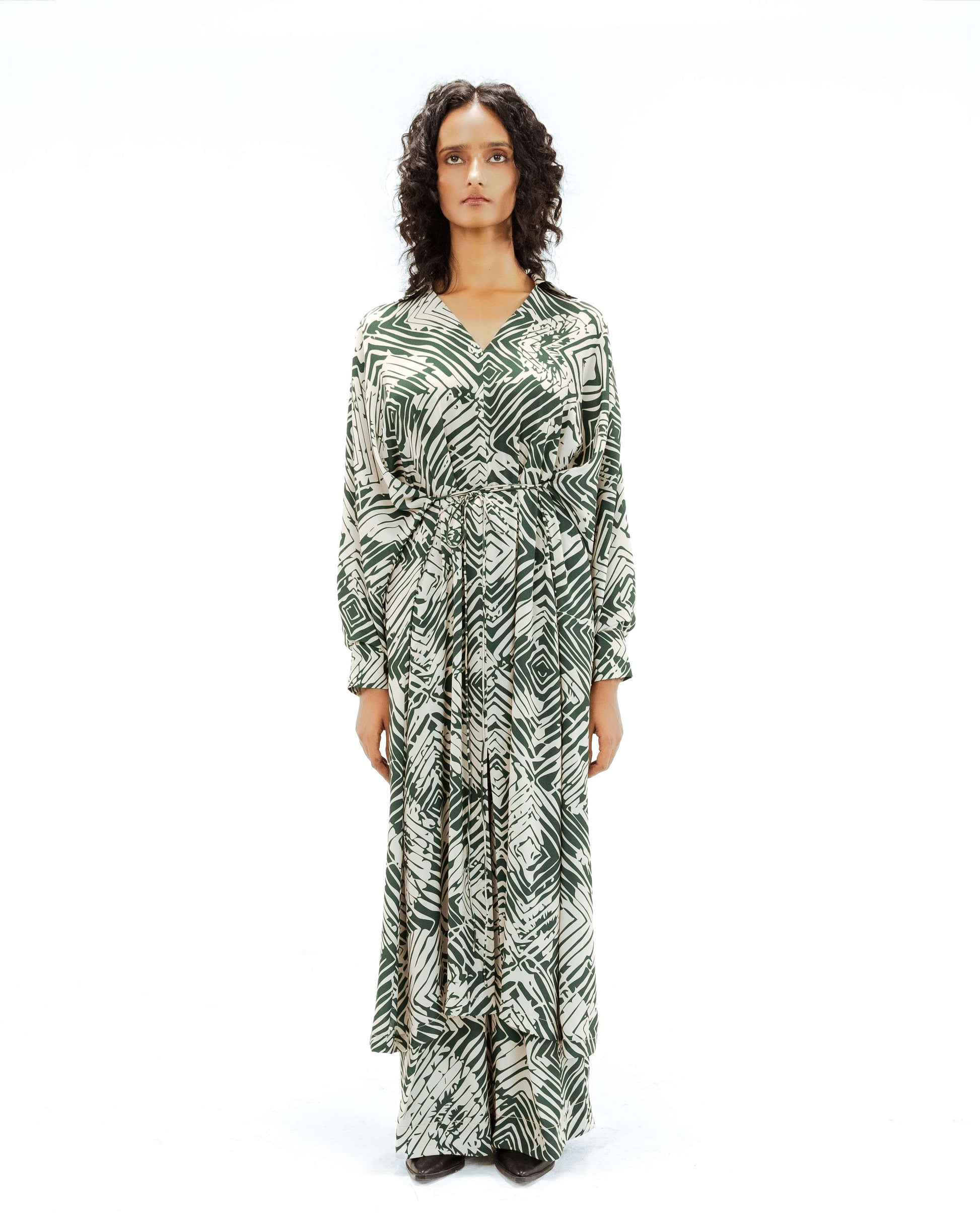 Model wearing the Leh clothing Florix Print Crepe Cape Dress, featuring a striking green and cream abstract print. This unique piece from the Rhythm of time collection highlights luxury upcycled fashion, ethical fashion, and eco-friendly design with its flowing handcrafted apparel silhouette.