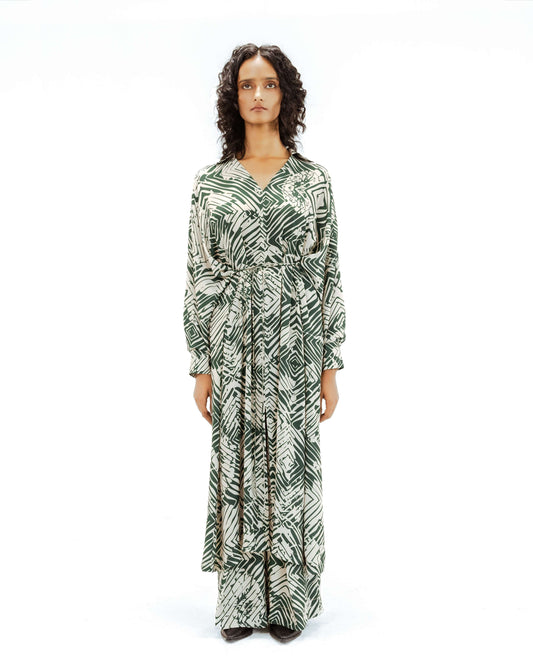 Model wearing the Leh clothing Florix Print Crepe Cape Dress, featuring a striking green and cream abstract print. This unique piece from the Rhythm of time collection highlights luxury upcycled fashion, ethical fashion, and eco-friendly design with its flowing handcrafted apparel silhouette.