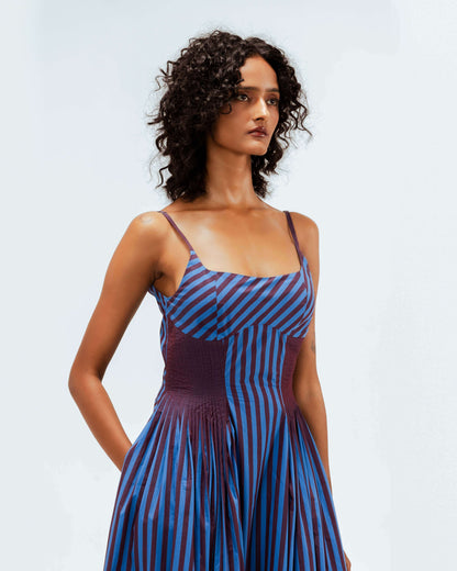 Leh Studios presents the Meva Dress from the Rhythm of time collection, a stunning blue and deep red striped dress worn by a model. This designer wear piece highlights artisanal craftsmanship, sustainable Indian fashion, and offers luxury upcycled fashion.