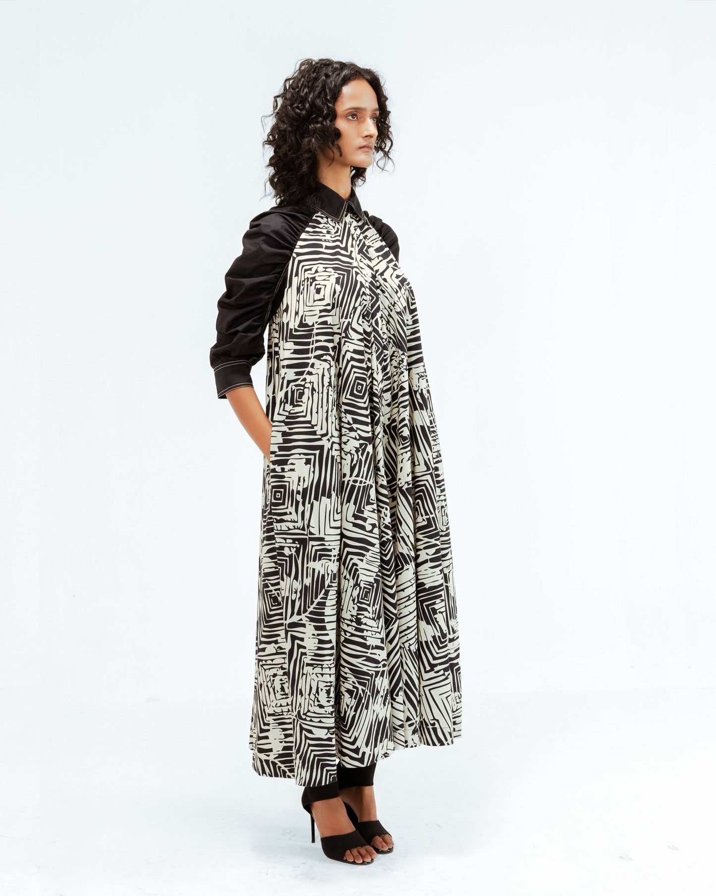 The Leh Studios Florix Print Fable Dress, part of the Rhythm of time collection, displayed on a model, highlights a unique black and white abstract print on a comfortable, billowy design with contrasting black sleeves. This upcycled clothing piece reflects artisanal craftsmanship and ethical fashion, offering sophisticated womens apparel that blends Indian traditions with contemporary style.