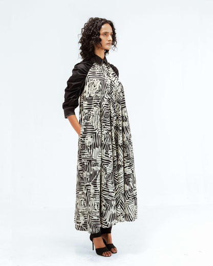 The Leh Studios Florix Print Fable Dress, part of the Rhythm of time collection, displayed on a model, highlights a unique black and white abstract print on a comfortable, billowy design with contrasting black sleeves. This upcycled clothing piece reflects artisanal craftsmanship and ethical fashion, offering sophisticated womens apparel that blends Indian traditions with contemporary style.