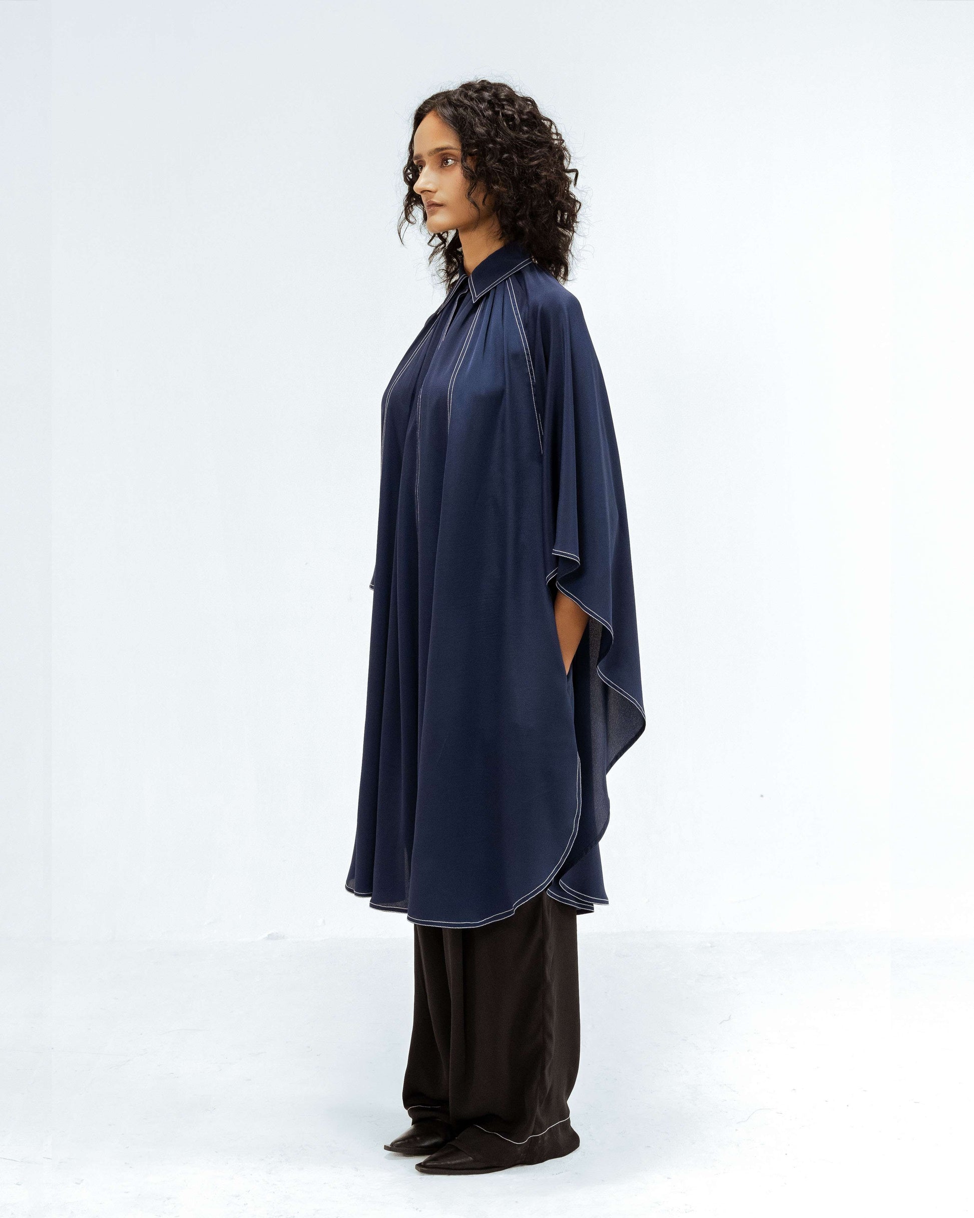 Leh Studios showcases the Selene Crepe Set, part of the Rhythm of Time collection. A model is featured in a luxurious navy top with handcrafted white topstitching and black flowing trousers, reflecting ethical fashion and artisanal craftsmanship in this upcycled clothing design.