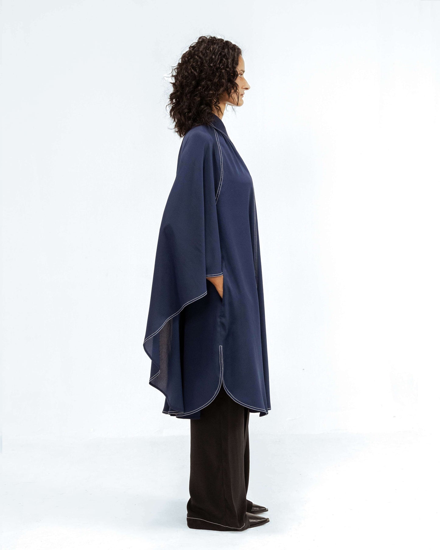 The Leh Studios Selene Crepe Set, part of the Rhythm of time collection, is modelled by a woman. This upcycled clothing ensemble includes a dark blue crepe top with intricate white stitching details and a relaxed, eco-friendly design, paired with wide-leg black trousers, highlighting ethical fashion for womens apparel.