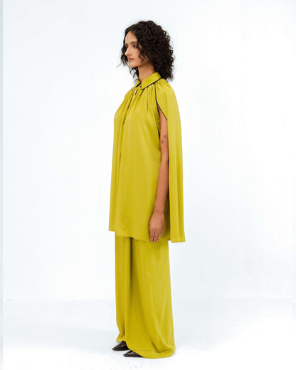 The Leh Studios Cherice Crepe Cordset, part of the Rhythm of time collection, is beautifully presented on a model in striking chartreuse green. This luxury upcycled fashion piece highlights artisanal craftsmanship and sustainable Indian fashion, featuring a unique cape-sleeved top and comfortable wide-leg pants.