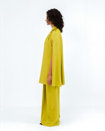 A model stands in profile, showcasing the Leh Studios Cherice Crepe Cordset in a vibrant chartreuse green. This sustainable fashion designer wear from the Rhythm of time collection features a flowing, cape-style top and wide-leg pants, embodying eco-friendly design and modern womens apparel.